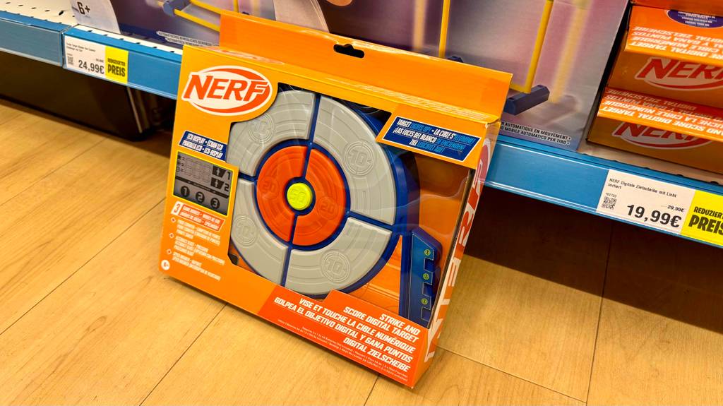 Eine getestete Nerf-Zielscheibe steht verpackt auf einem Holzboden.