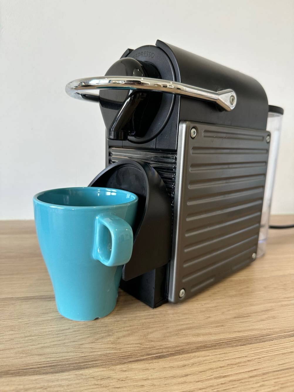 Nespresso-Maschine steht mit einer Tasse auf einer Arbeitsplatte.