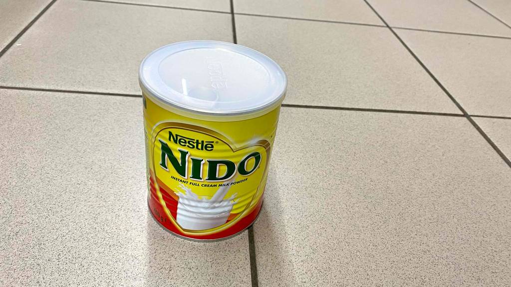 Eine geschlossene Dose getestetes Vollmilchpulver, von oben betrachtet, steht auf einem Fliesenboden.