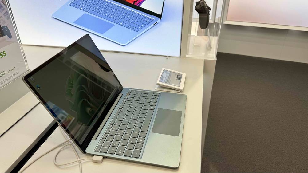 Seitenansicht eines aufgeklappten Netbooks im Test auf einer hellen Fläche mit Preisangabe.
