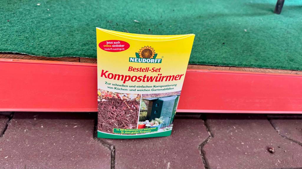 Eine Packung Kompostwürmer steht zum testen auf einem Pflastersteinboden.