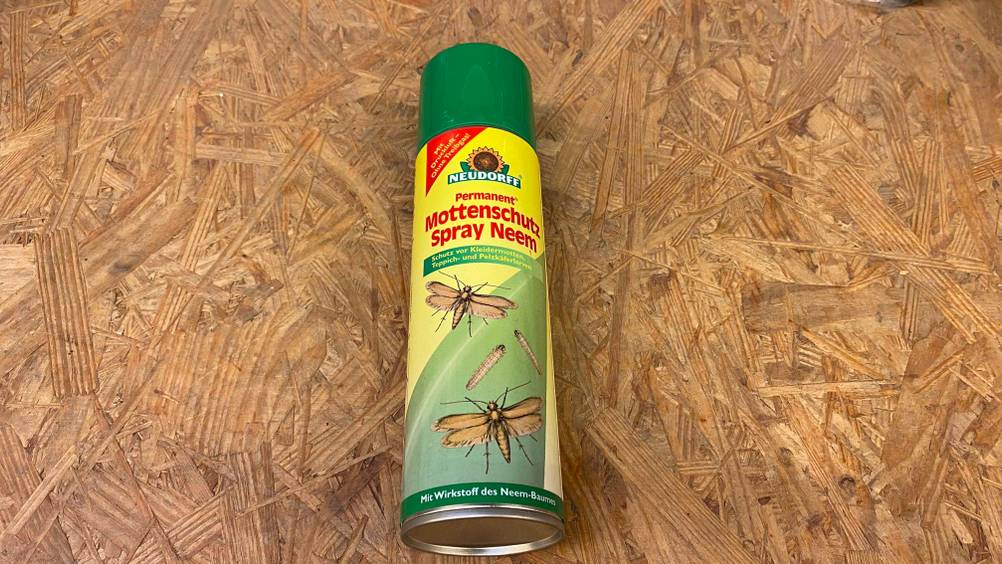 Nahaufnahme des Bodens einer Dose des getesteten Mottensprays auf einer Holzfläche.