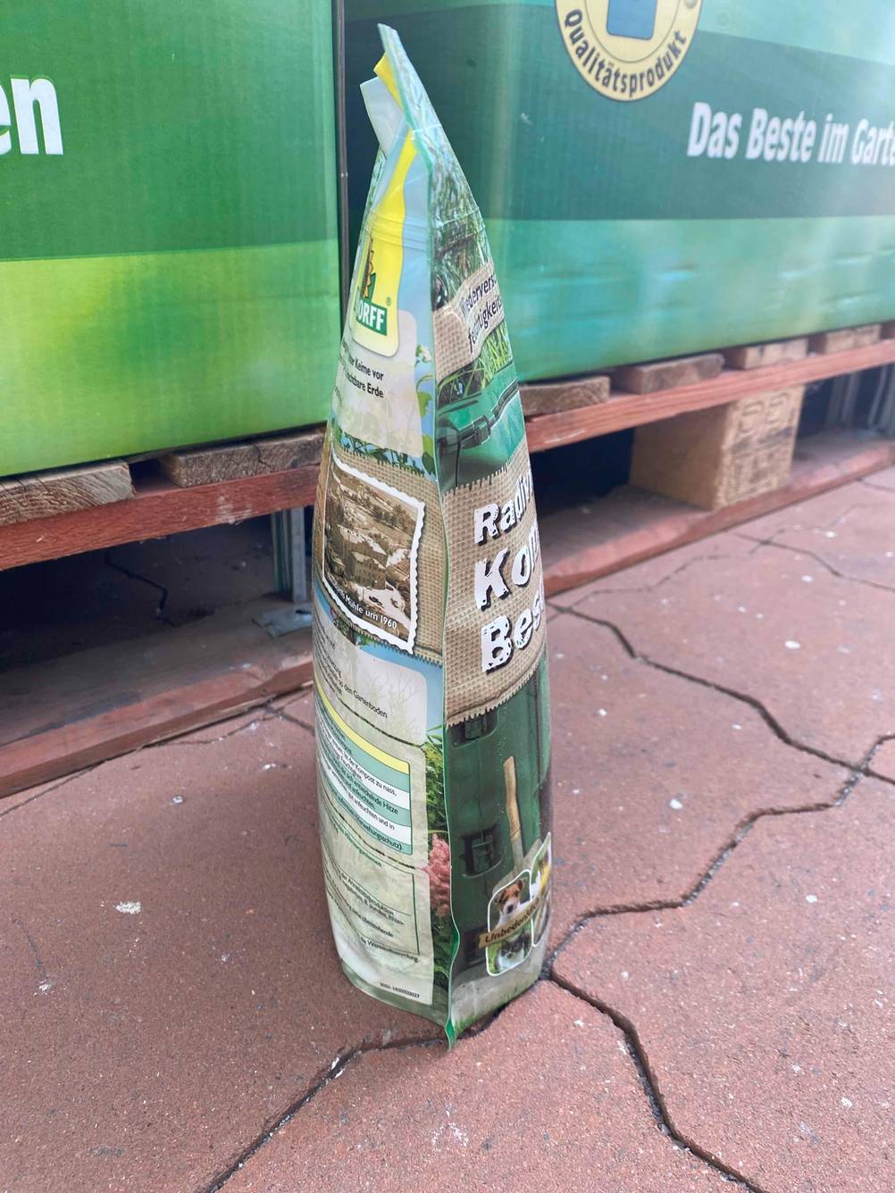 Eine Packung des getesteten Kompostbeschleuniger von der Seite auf einem Steinboden stehend.