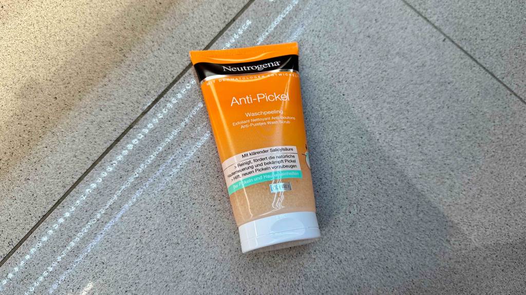 Ein getestetes Neutrogena-Peeling liegt auf grauen Fliesen.