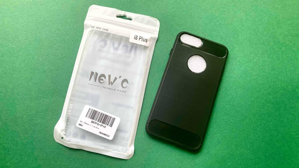 iPhone-8-Plus-Hüllen-Test: eine schwarze Hülle liegt mit Blick auf die Rückseite neben seiner Verpackung auf einem grünen Untergrund.
