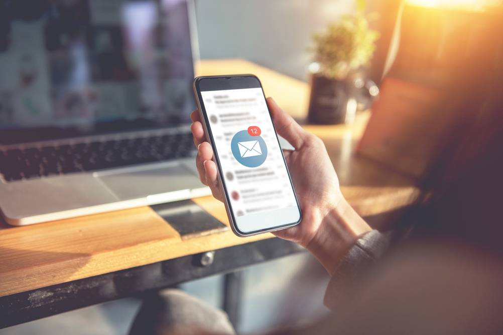 Mann hält ein Smartphone mit einer getesteten Newsletter-Software in der Hand.