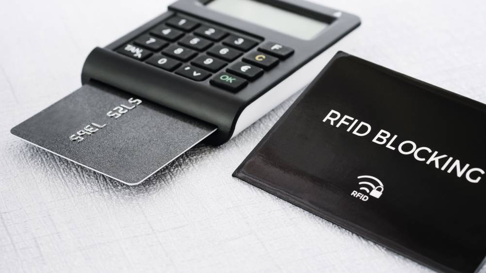 Ein getesteter RFID-Blocker und ein Lesegerät mit Kreditkarte auf weißem Hintergrund.