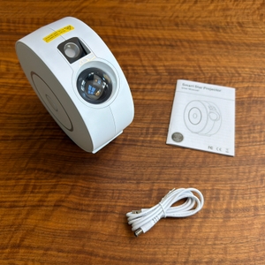 Der Lieferumfang vom Nigecue-Sternenhimmel-Projektor HR-002 liegt auf einem Tisch.