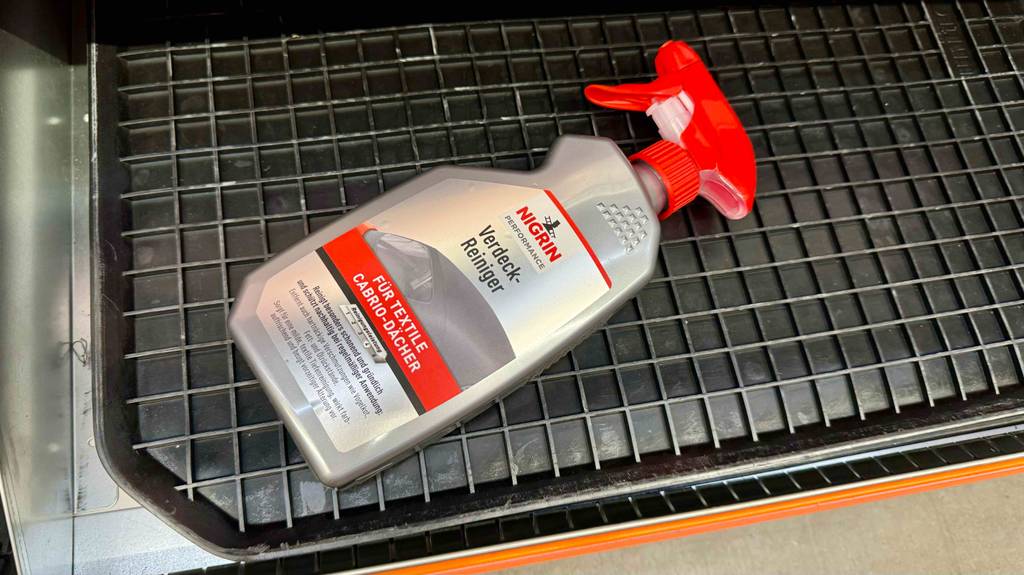 Eine Flasche Cabrioverdeck-Imprägnierung liegt zum Testen auf einem schwarzen Plastikgitter.