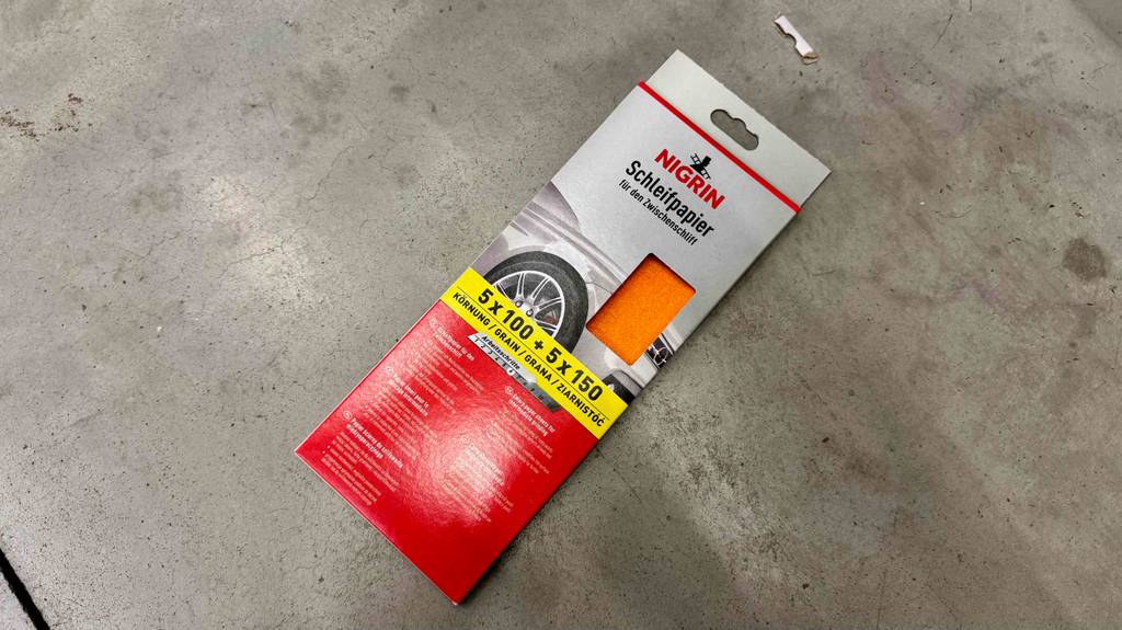 Eine Packung getestetes Schleifpapier liegt auf einem grauen Boden.