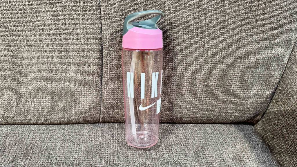 Eine getestete Trinkflasche mit Strohhalm steht in einem Sofaeck.