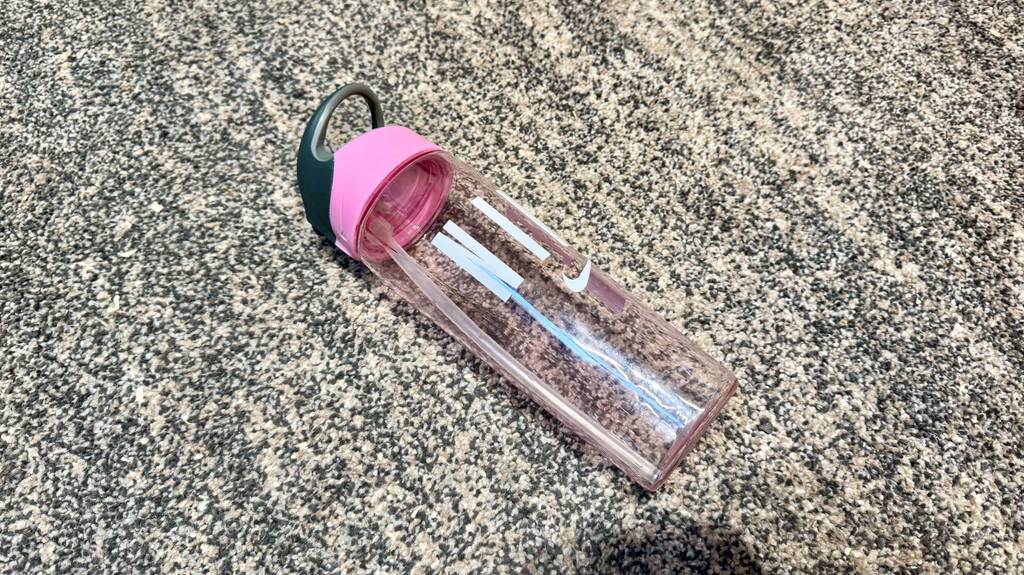 Eine getestete Trinkflasche mit Strohhalm liegt auf einem schwarz-weiß gemusterten Teppich.