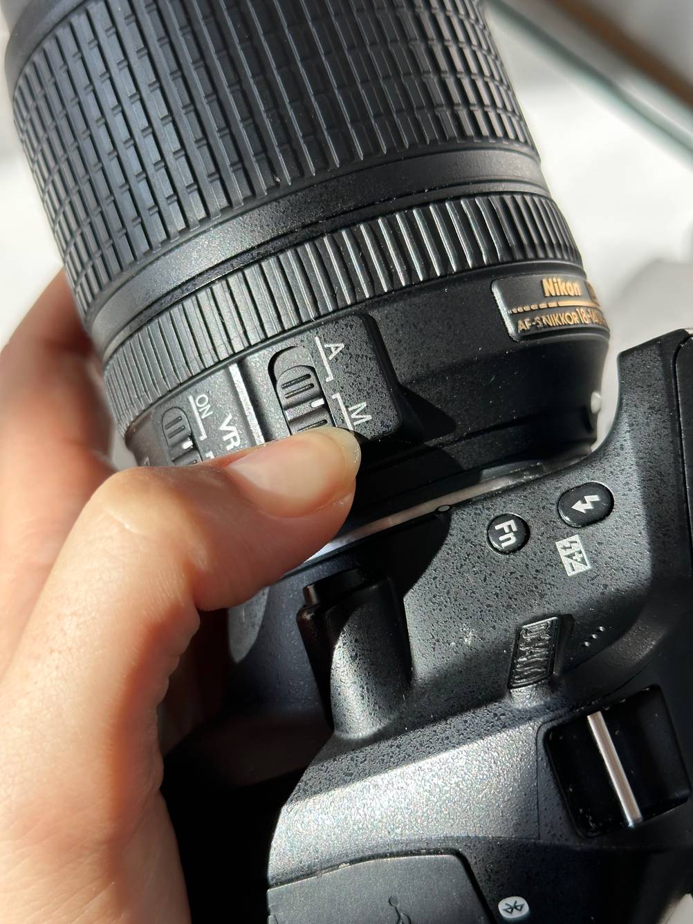 Eine Hand betätigt einen Schalter an dem getesteten Nikon-Objektiv.