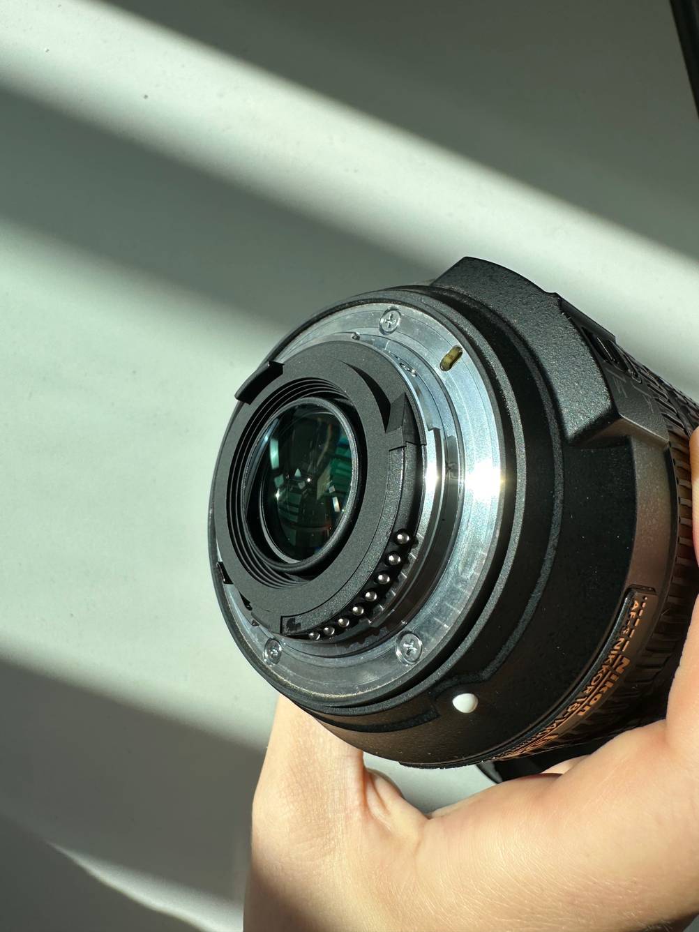 Nahaufnahme des Kameramount eines getesteten Nikon-Objektivs von einer Hand gehalten.