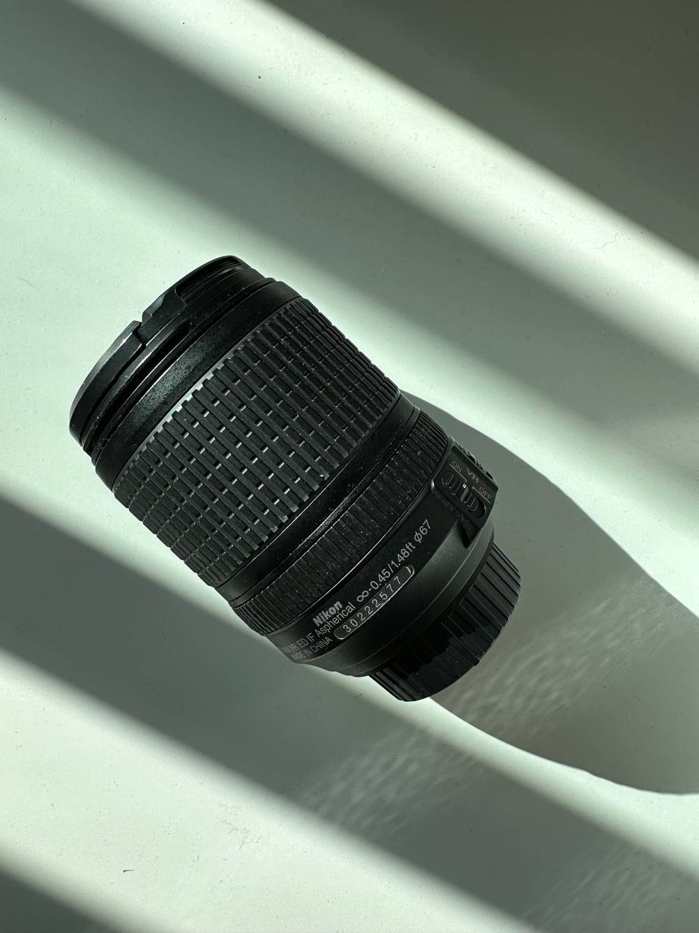 Ein getestetes Nikon-Objektiv liegt auf einer weißen Oberfläche. 