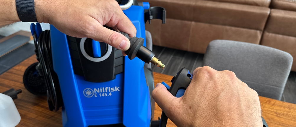Zwei Hände stecken den Schlauch an den Griff des Nilfisk E 145.4-9 X-TRA
