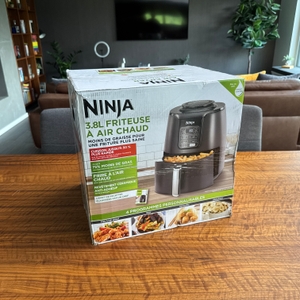 Der Karton der Ninja AF100EU steht auf einem Holztisch.