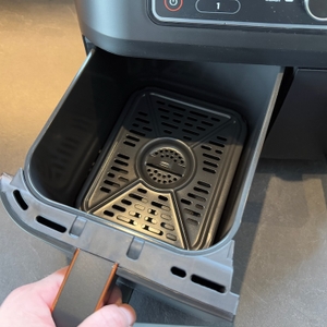 Linker Behälter der Ninja Foodi MAX AF400EUCP wird von einer Hand herausgezogen