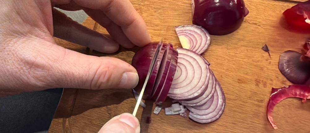 Mit einem kleinen Messer aus dem Ninja-Foodi-Messerblock wird eine Zwiebel geschnitten.