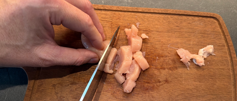 Mit einem Messer aus dem Ninja-Foodi-Messerblock wird Fleisch geschnitten.