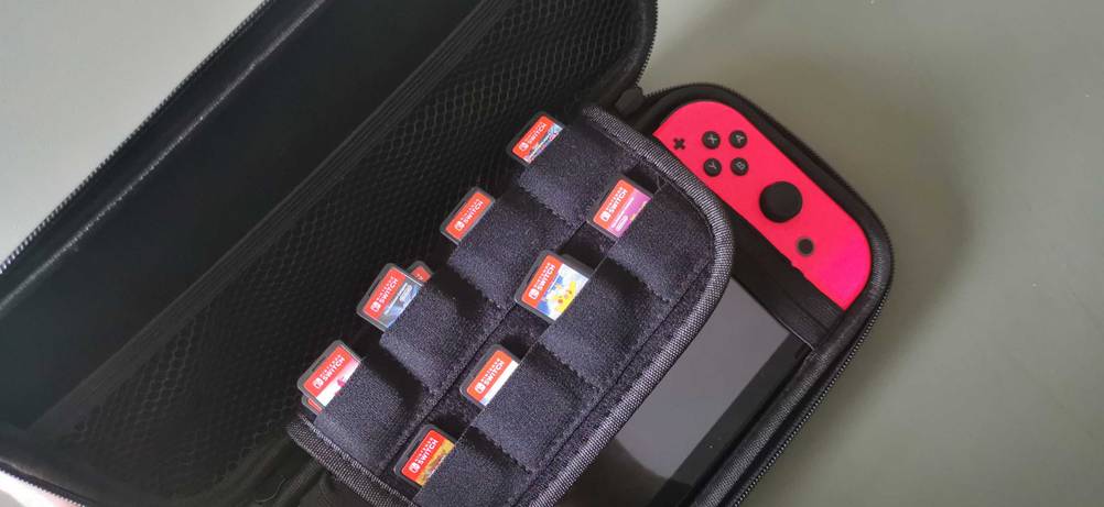 Handheld Konsole im Test: in einer Spieleaufbewahrungstasche sind viele Spiele, im Hintergrund eine tragbare Konsole.