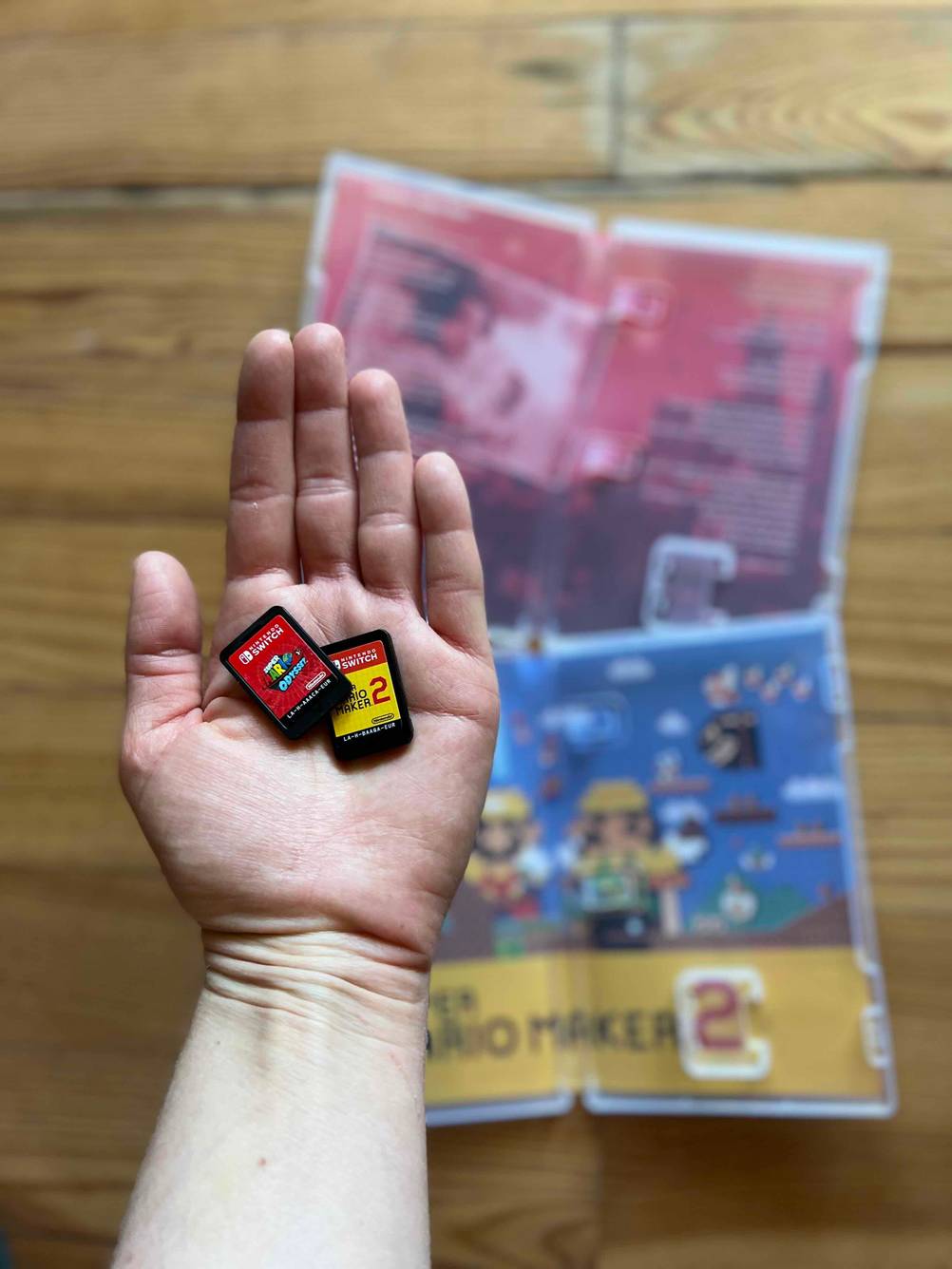 In einer Hand liegen zwei getestete Nintendo Switch Spiele, im Hintergrund die Hüllen.