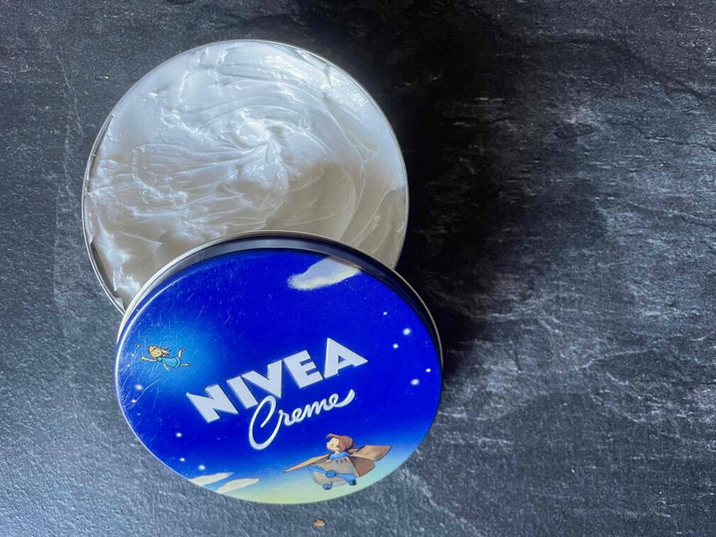 Im Test: Nivea-Creme in einer geöffneten Dose befindet sich auf einem grauen Untergrund.