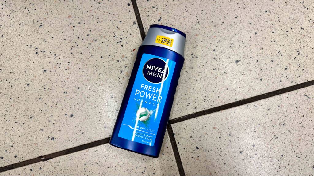 Eine Flasche getestetes Männer-Shampoo liegt auf hellen Fliesen.