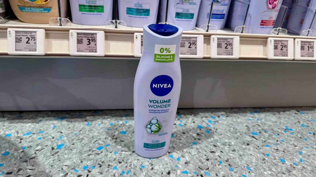 Im Test: NIVEA Shampoo steht in einer Kunststoffflasche auf dem Boden vor einem Regal im Drogeriemarkt.