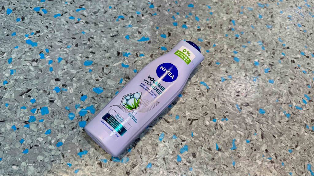 Eine Kunststoffflasche mit NIVEA Shampoo im Test liegt auf dem Linoleumboden.