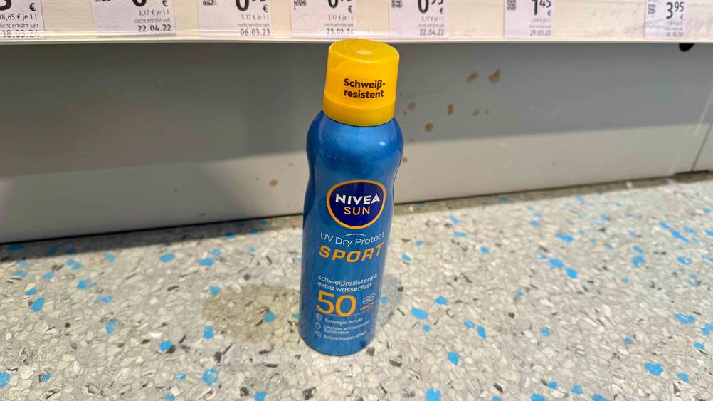 Vor einem Regal steht eine Dose des getesteten Nivea-Sonnensprays auf dem Boden.