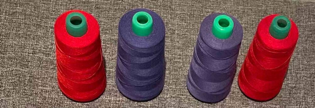 Overlockgarn-Test: rotes und violettfarbenes Garn auf Rollen von oben betrachtet.