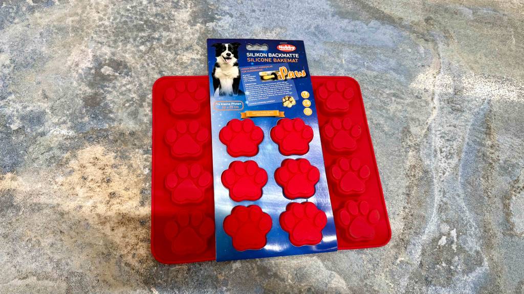 Eine getestete Backmatte für Hundekekse liegt im Kartonblister auf einem Boden.