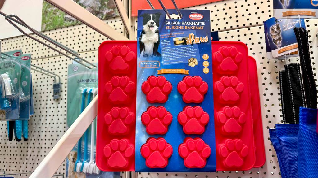Mehrere Backmatten für Hundekekse hängen zum testen zwischen anderen Produkten in einem Regal.