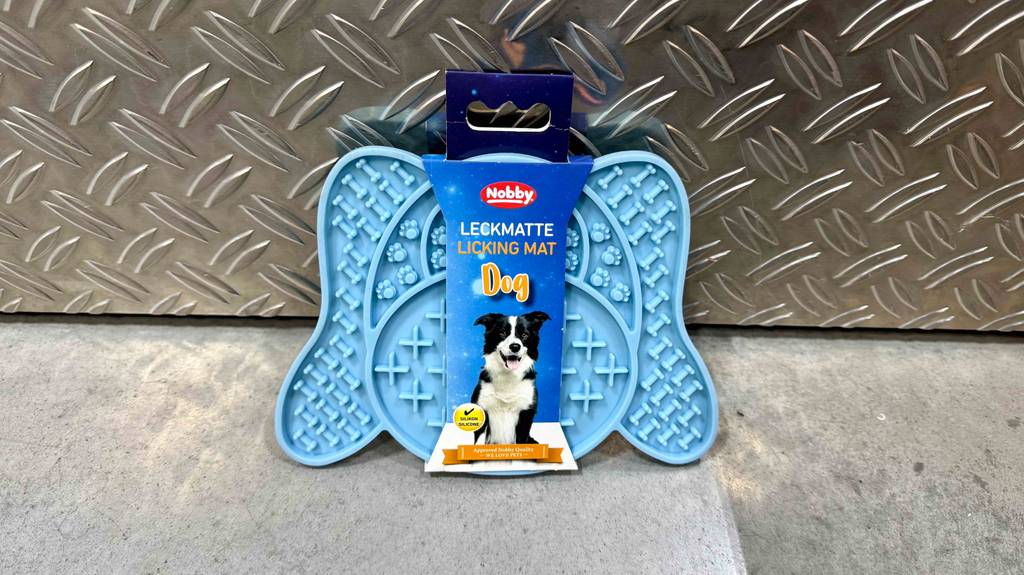 Die hellblaue Hunde-Leckmatte im Test lehnt an einer Aluminiumbox.