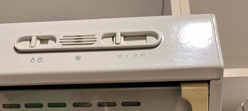 Detailaufnahme von Licht- und Umluft-Einstellschalter einer weißen Dunstabzugshaube im Test.