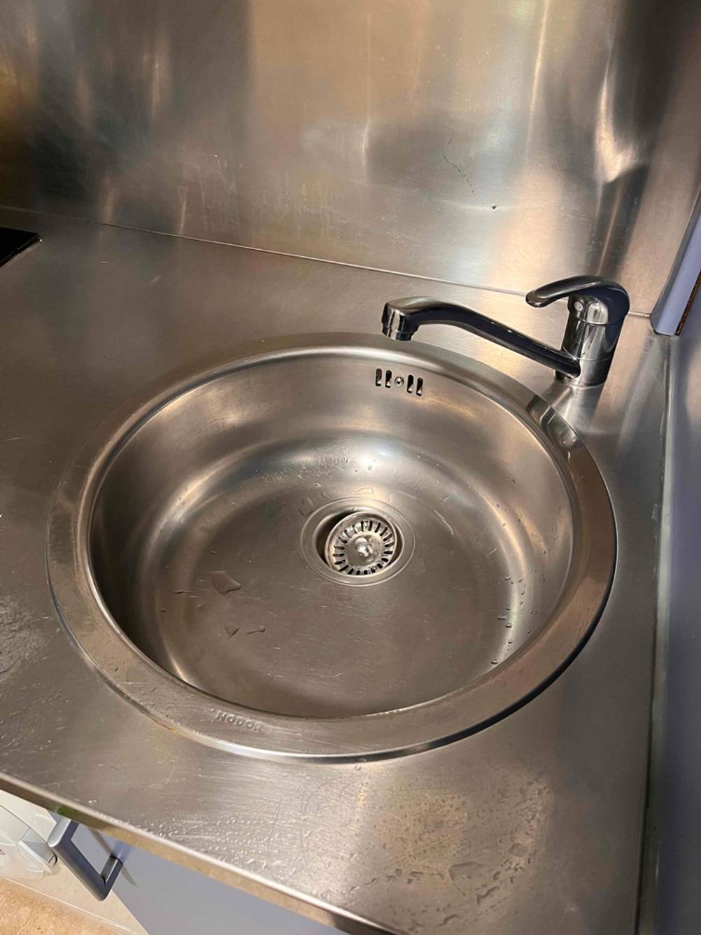 Eine eingebaute Edelstahl-Küchenspüle im Test neben einer Spülbecken-Armatur von schräg oben betrachtet.