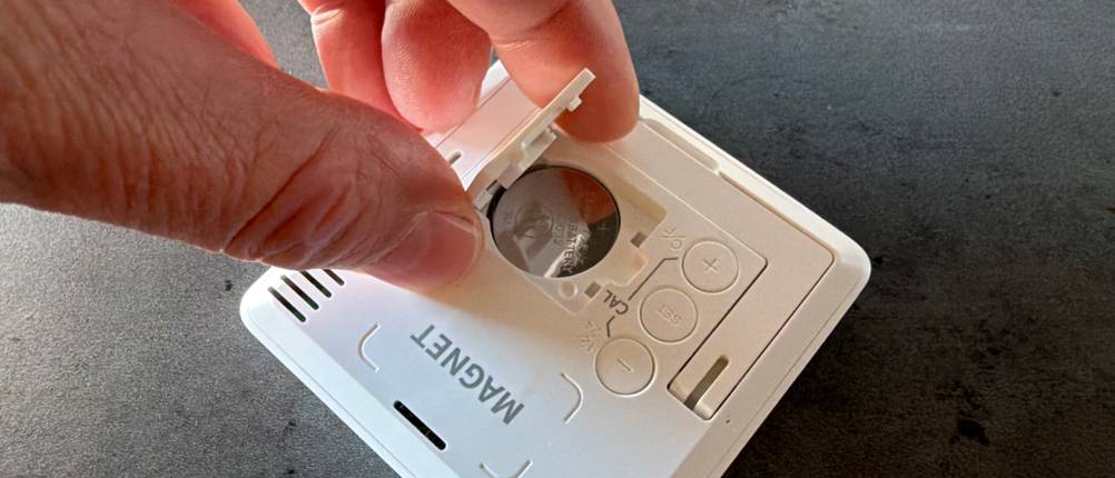 Eine Hand entfernt die Batterieabdeckung vom Noklead-Hygrometer