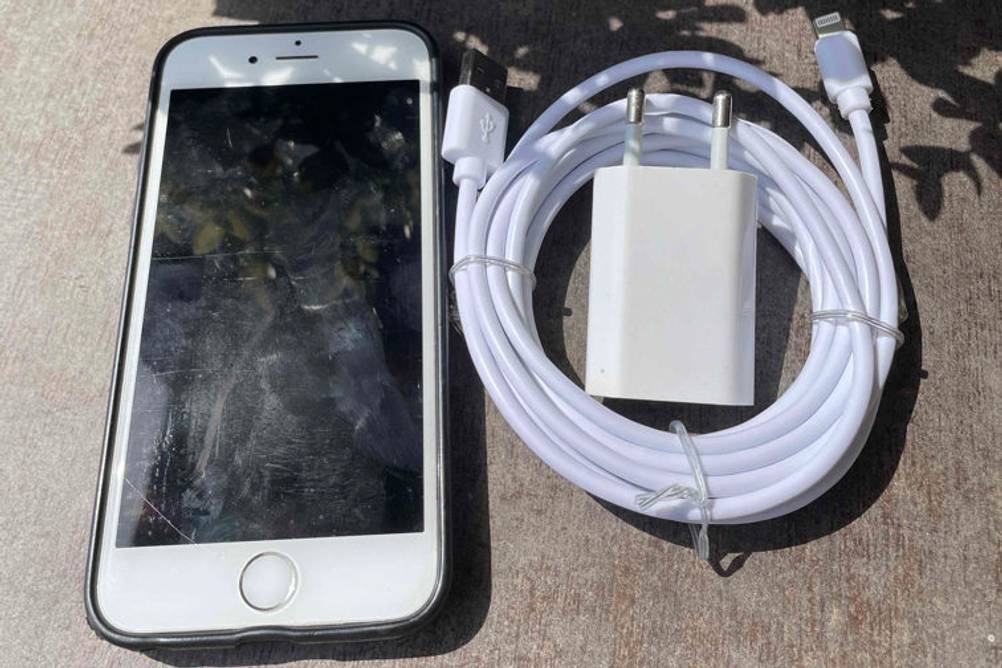 Weißes Lightning-Kabel im Test liegt zusammengerollt neben einem iPhone.