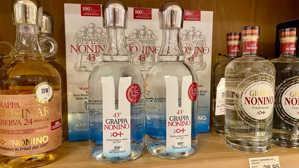 Grappa getestet: Zwei Flaschen stehen vor ihrer Originalverpackung neben anderen Produkten im Regal.
