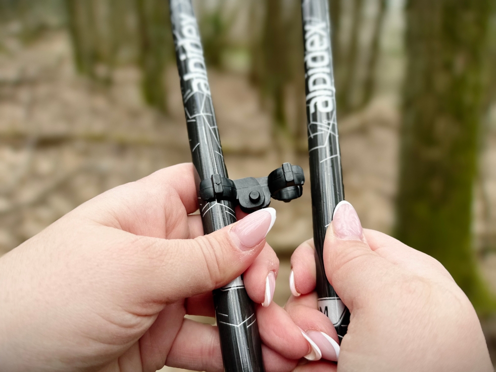 Zwei Hände halten die Clip-Verbindung zweier Alpidex-Nordic-Walking-Stöcke. Die Verbindung dient zur Fixierung der Einzelteile.