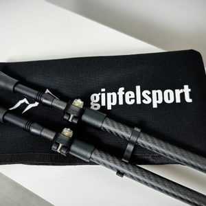 Ein vollständiges Gipfelsport-Nordic-Walking-Set liegt auf einem Tisch. Enthalten sind Stöcke, Schlaufen, Pads, Teller und eine Transporttasche.