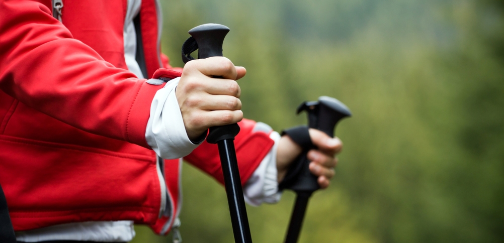 Nahansicht von Händen, die Griffe von Nordic-Walking-Stöcken halten.