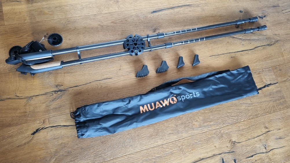 Muawo-Sports-Nordic-Walking-Stöcke mit Aufsätzen und Verpackungshülle liegen auf dem Boden zum Zeigen.
