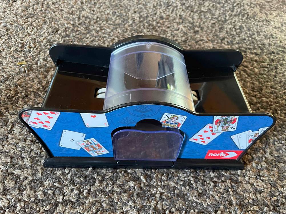 Eine Kartenmischmaschine mit klassischen Spielkarten als Aufdruck.
