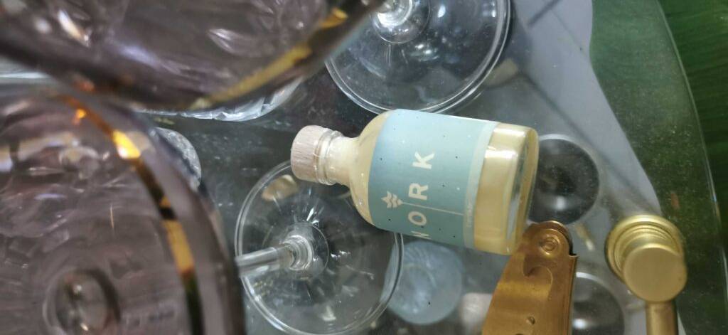 Eierlikör im Test: eine kleine Flasche Eierlikör der Marke Nork liegt inmitten von Gläsern auf einem Glastisch.