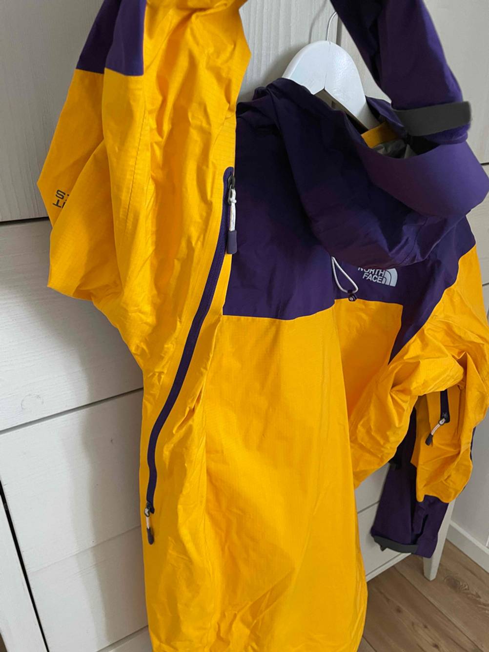 Ansicht einer gelb-blauen getesteten Unisex-Regenjacke, mit Fokus auf den Reißverschluss im Achselbereich.