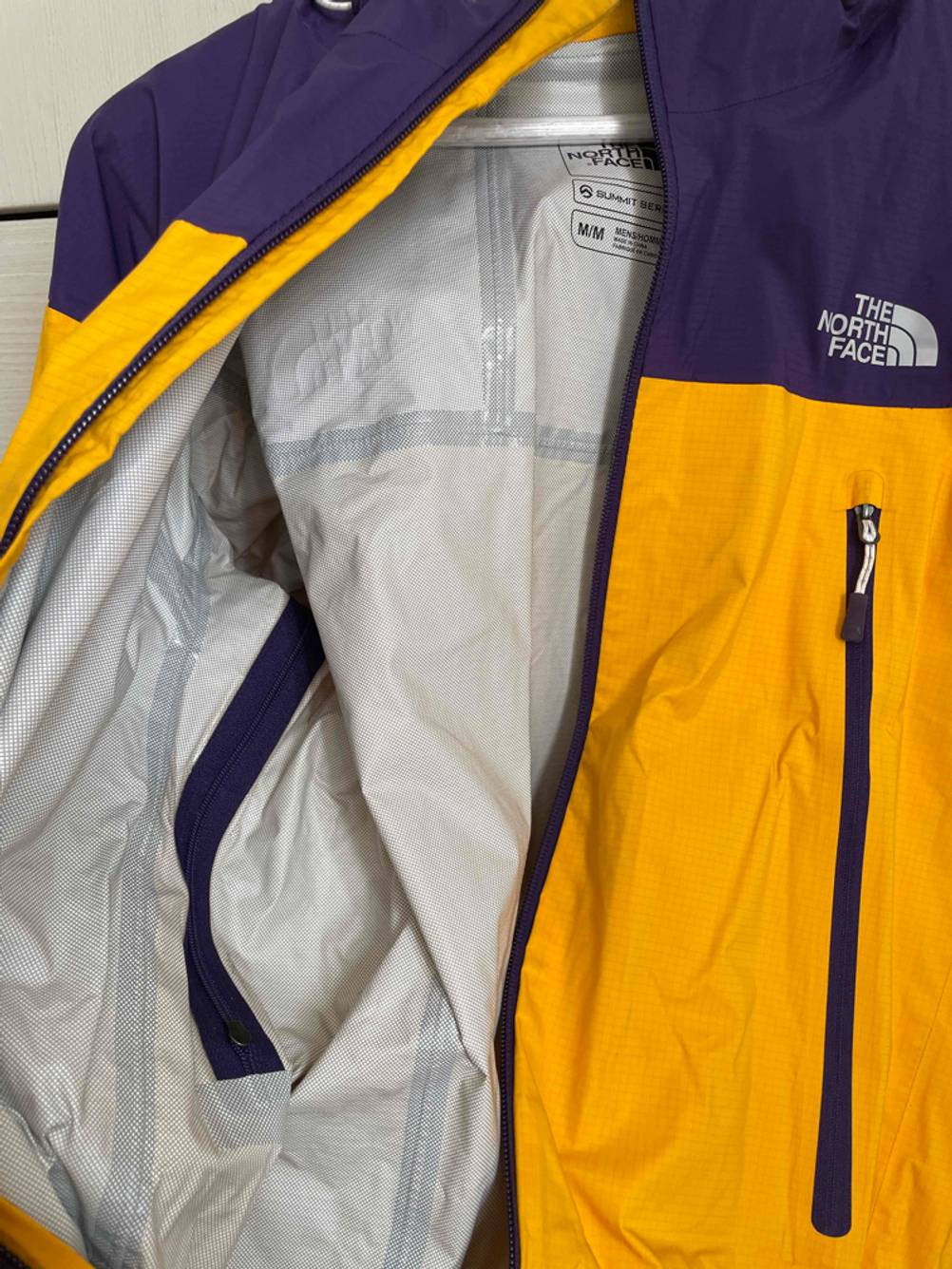 Nahaufnahme des hellgrauen Innenfutters von einer gelb-blauen The North Face Unisex-Regenjacke im Test.