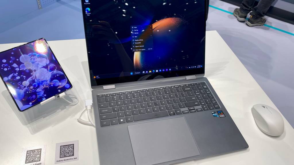 Getestetes Notebook-mit-Touchscreen befindet sich zwischen einer Computermaus und einem Tablet. 
