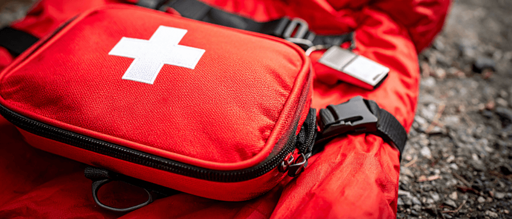 Notfall-Schlafsack im Test: Ein Erste-Hilfe-Set auf einer roten Decke.